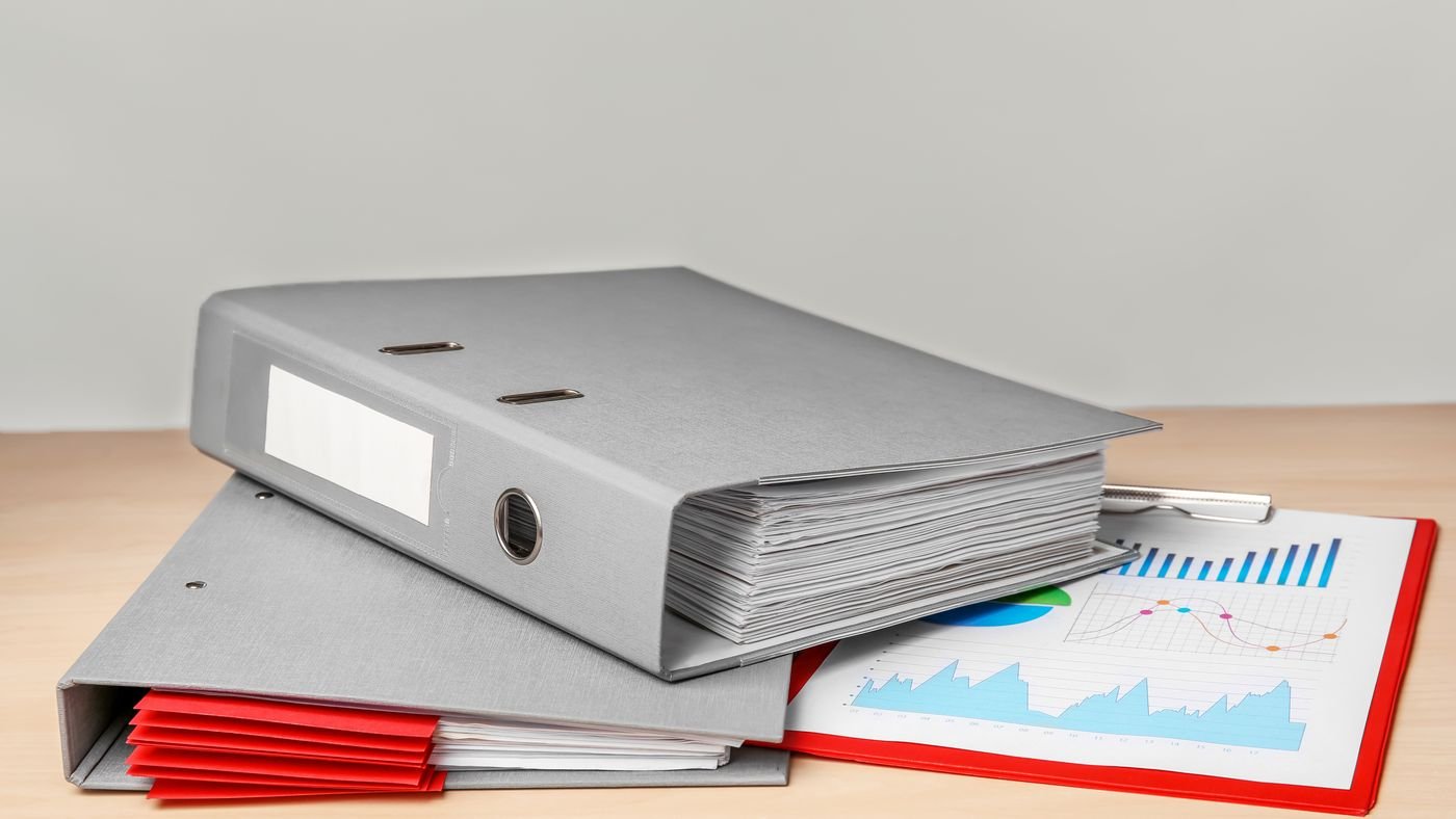 Classeurs d'archives et pièces comptables empilés sur un bureau